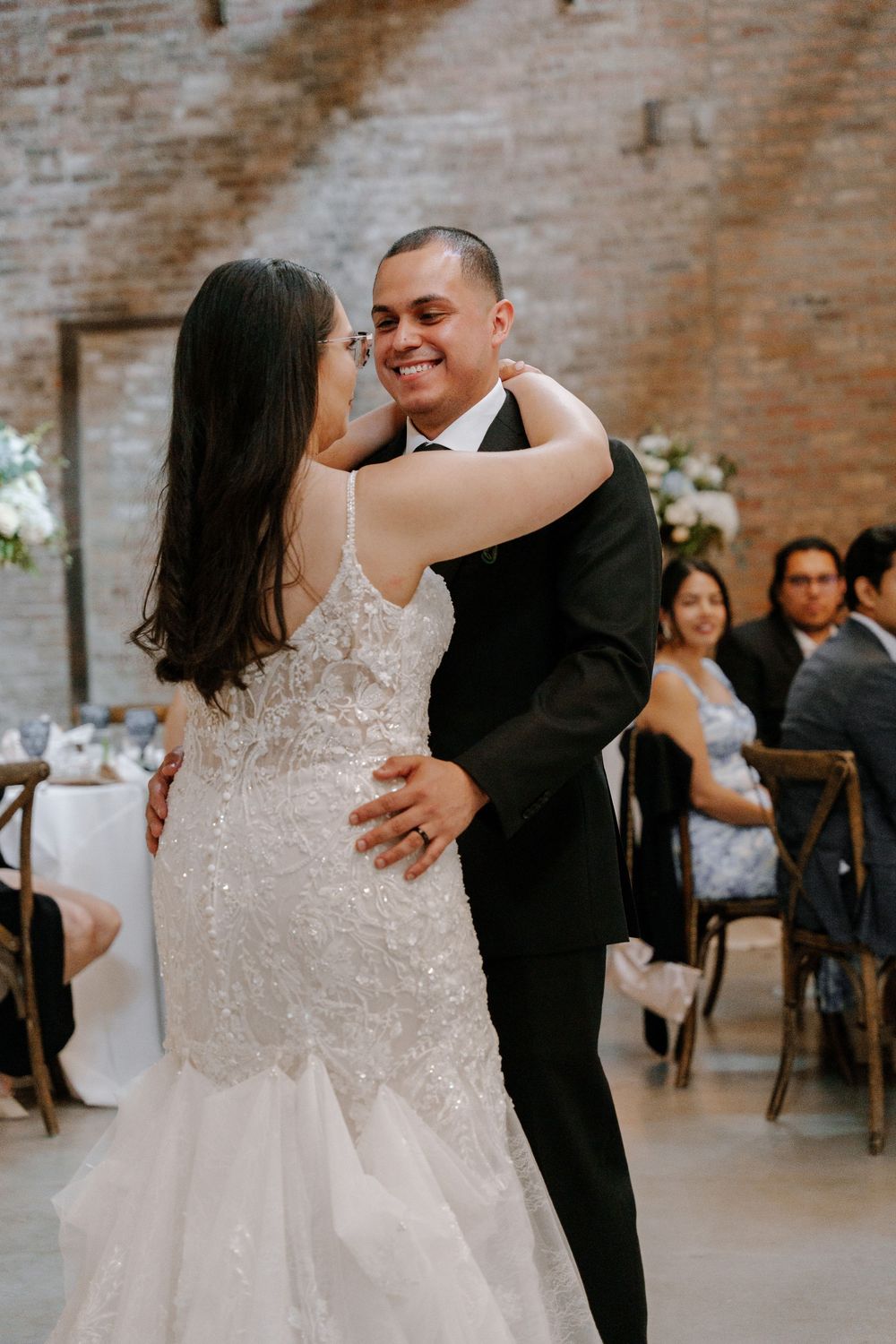 A couple sharing a romantic dance moment in an elegant wedding venue with brick walls.