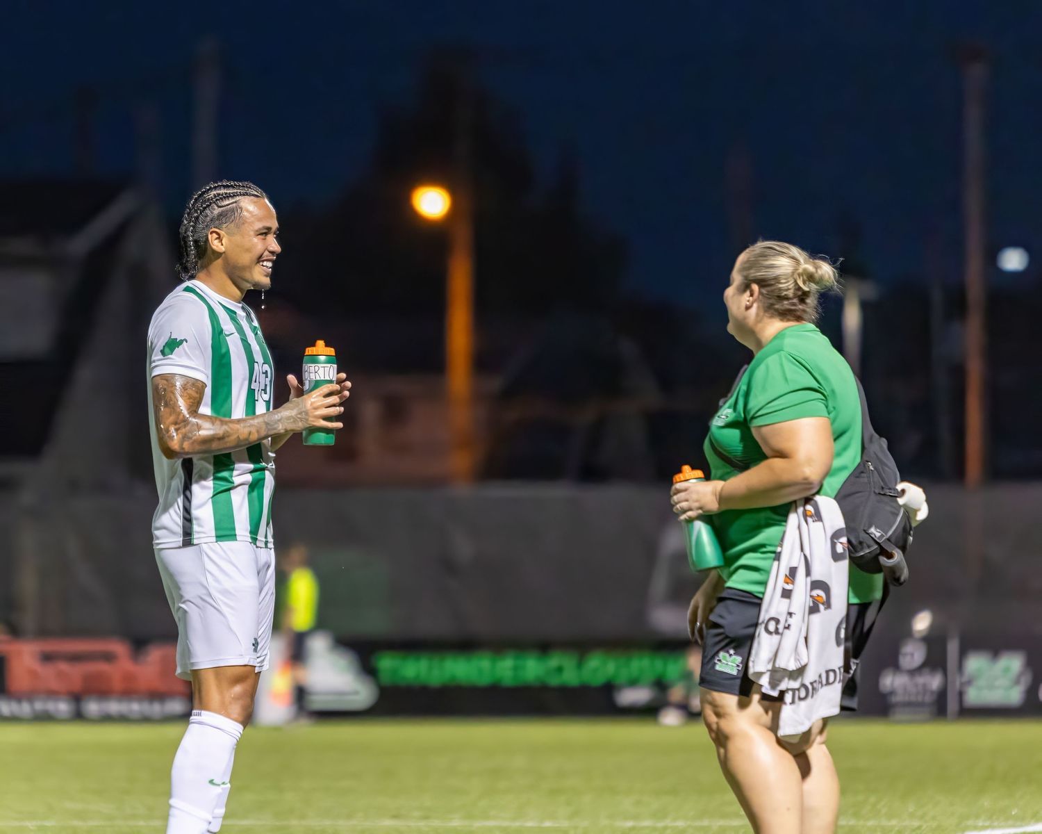 An intense rugby match in progress with players in green and white jerseys competing for the ball on the field.
