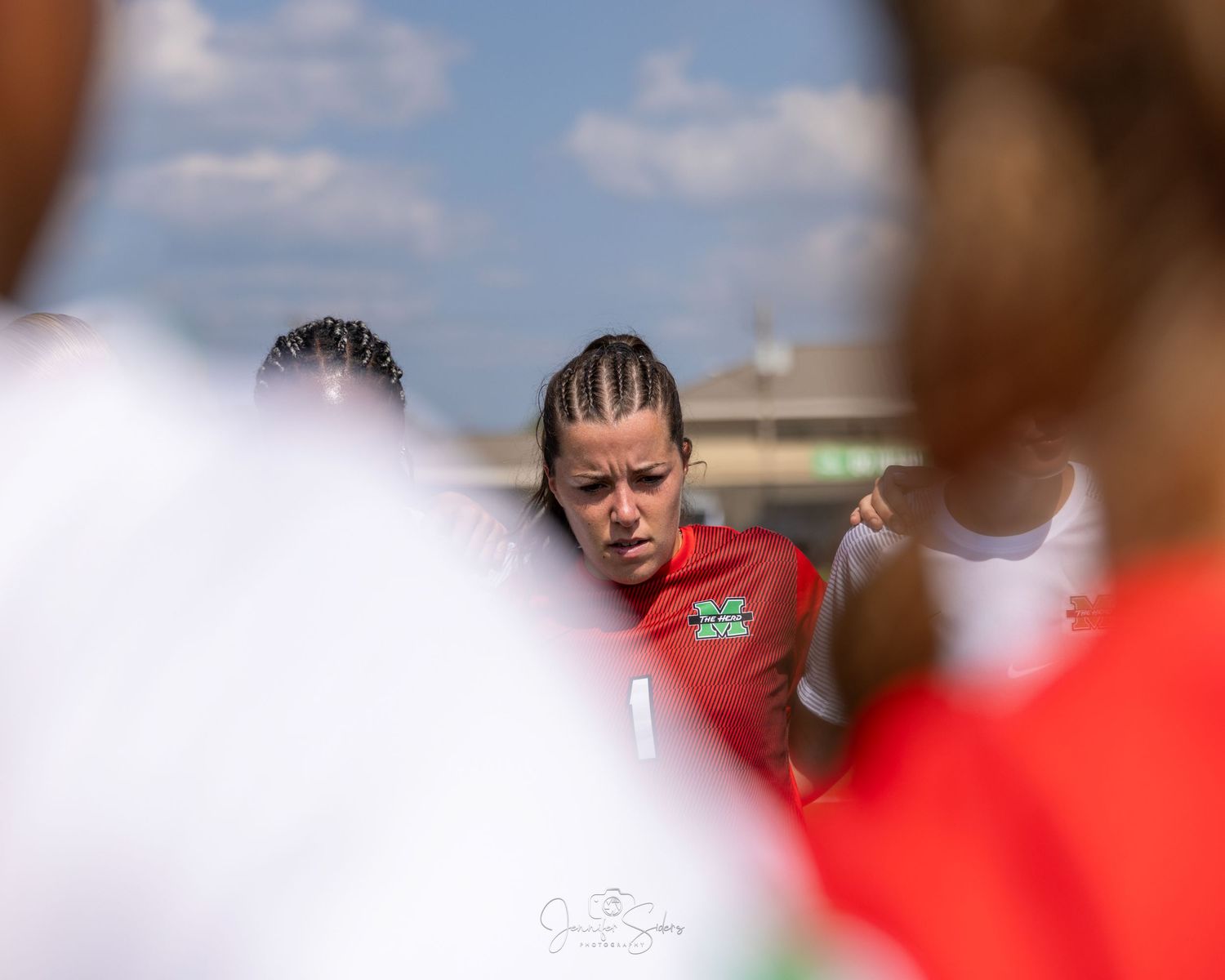 Soccer players engage in a heated discussion during an intense match on a sunny day.