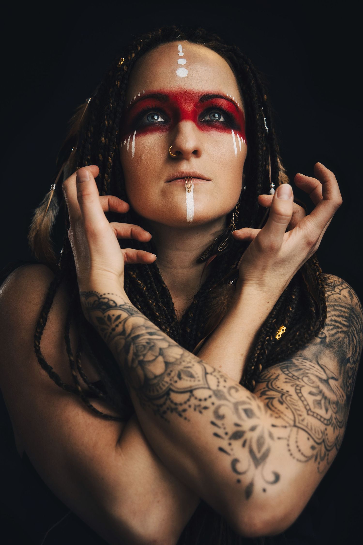 Kreativt porträtt i studio Malmö – kvinna med flätor, röd ansiktsmålning och intensiv blick | Werlerstam Photography