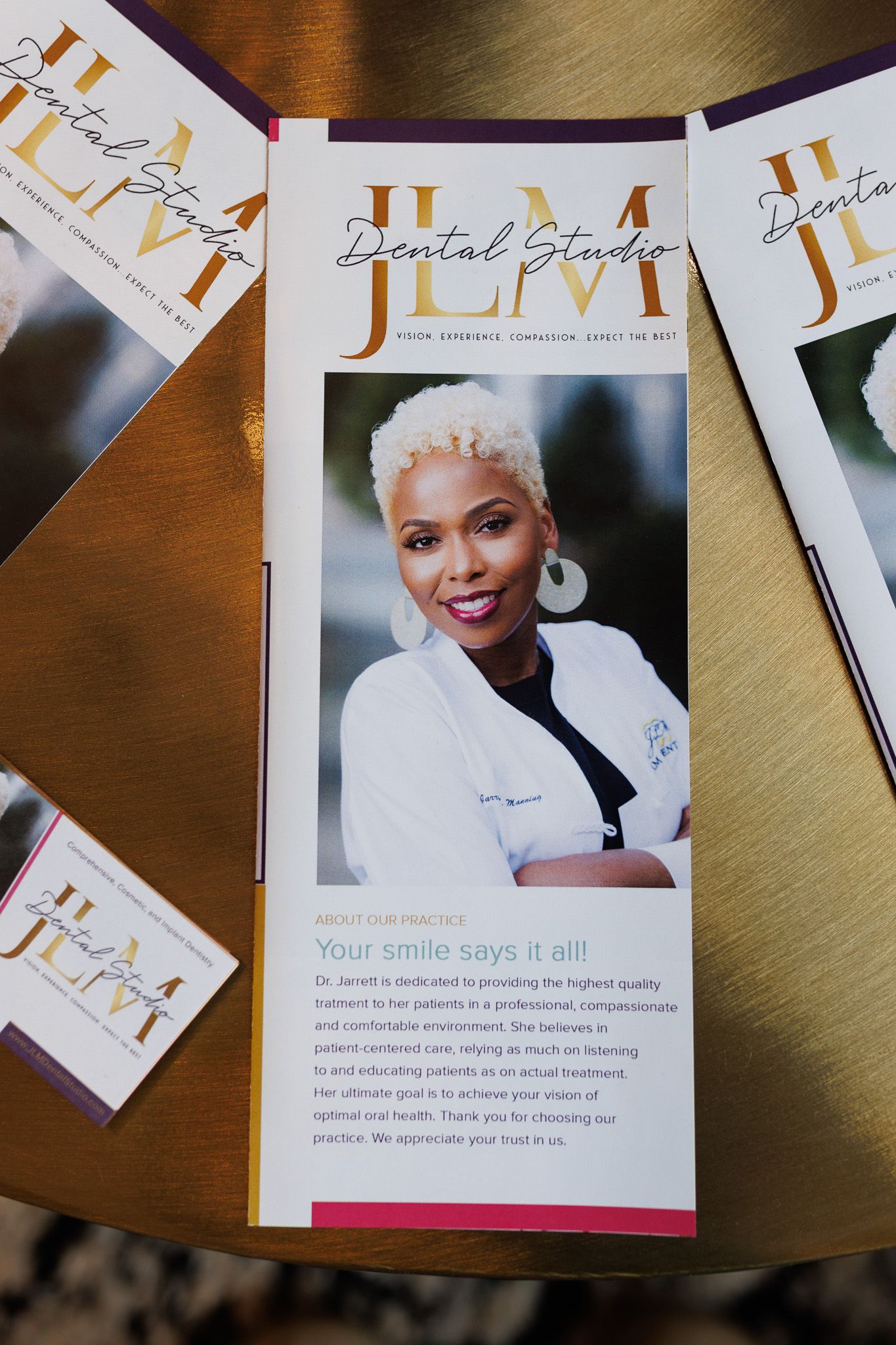 Marketing materials and brochures showing professional business documents with orange accents laid out on a wooden surface.