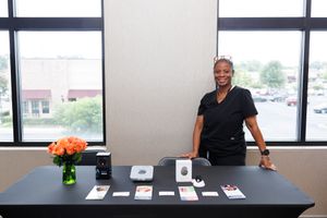 Professional seated behind a gray tabletop display with marketing materials and product cards laid out neatly.