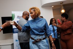 People interacting and socializing at an indoor business event with HydraTech signage in the background.