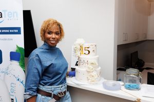 Standing in a modern kitchen interior with a blue turtleneck sweater and jeans next to a decorative white cake.