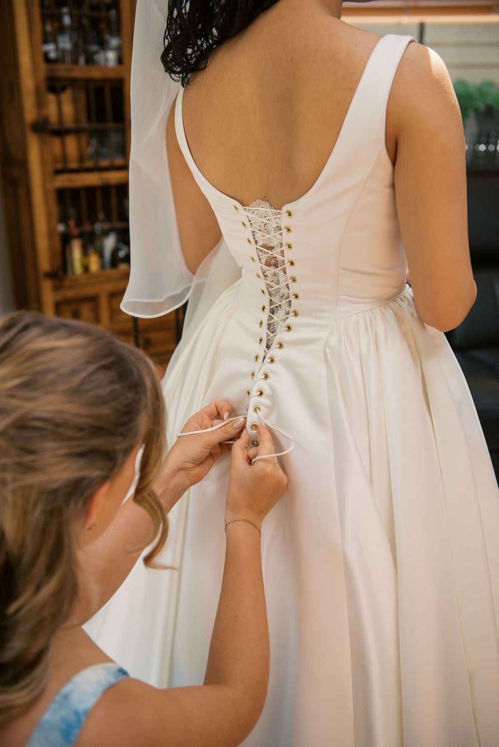 Close-up sequence of hands lacing up the back of a white wedding dress.