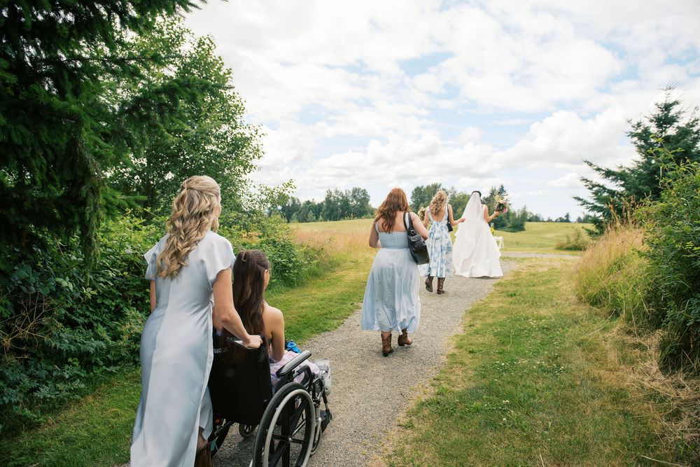Wedding guests walking up a scenic hillside path surrounded by greenery.
