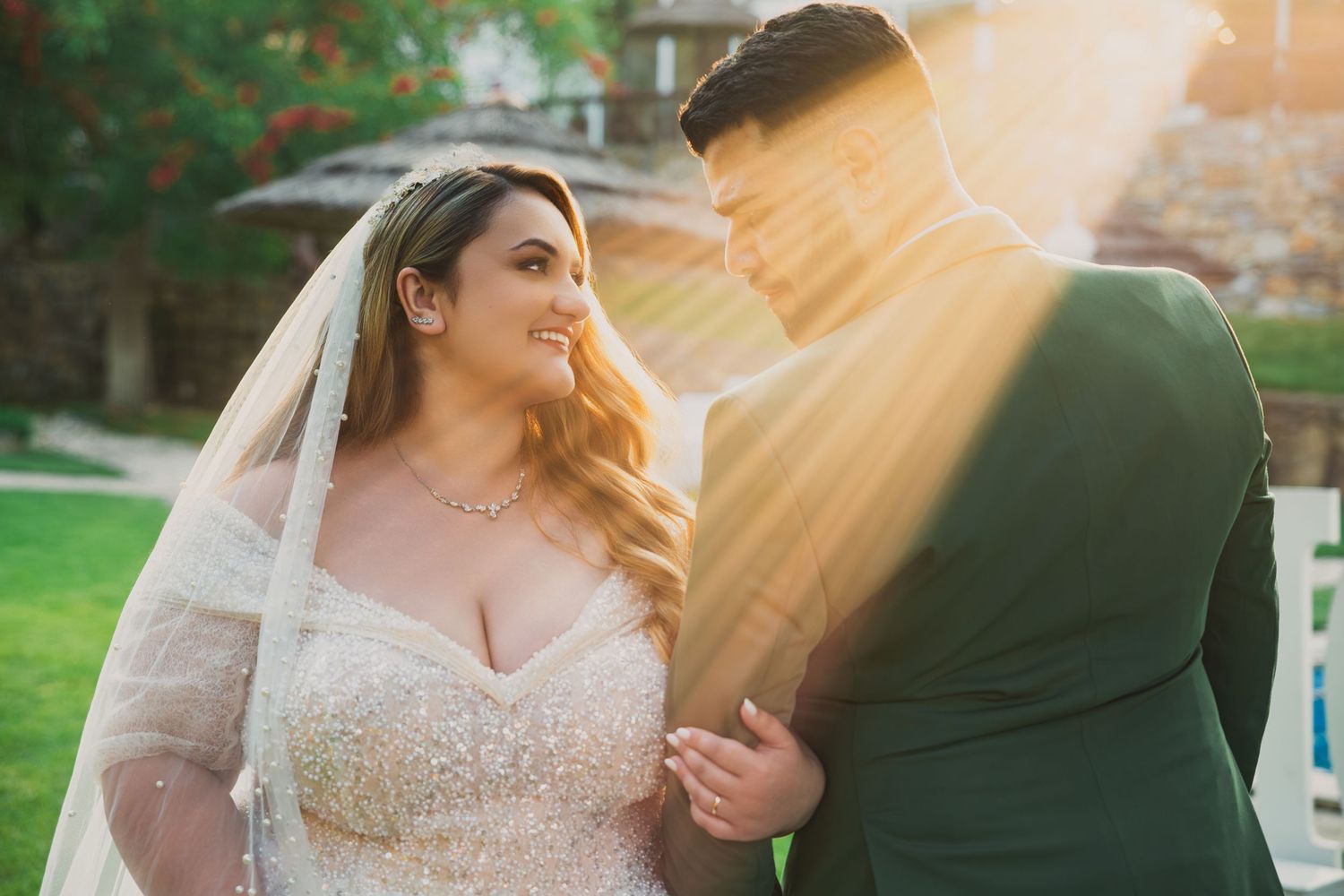 Couple sharing intimate moment in golden sunlight during outdoor wedding.