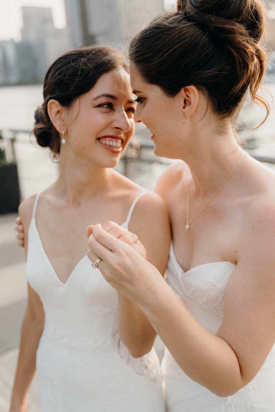 Two brides share an intimate moment in matching white wedding dresses at the Sanctuary Roosevelt Island NYC