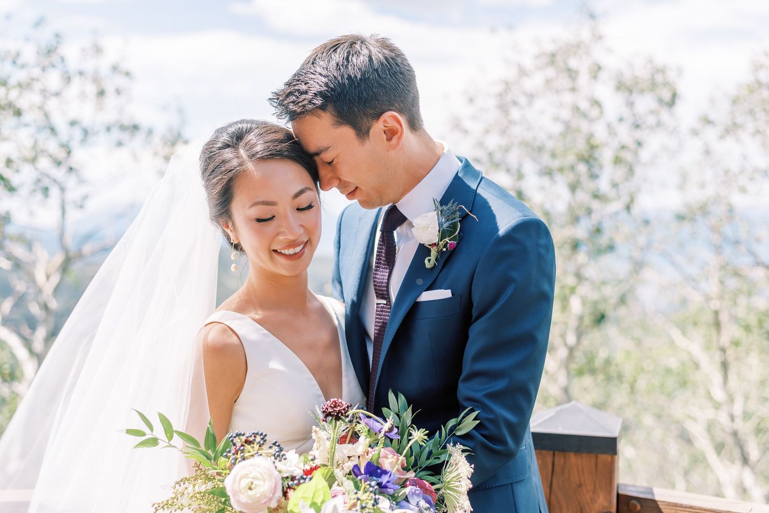A wooden hexagonal wedding arch with white fabric draped stands in a lavender field on a sunny day.