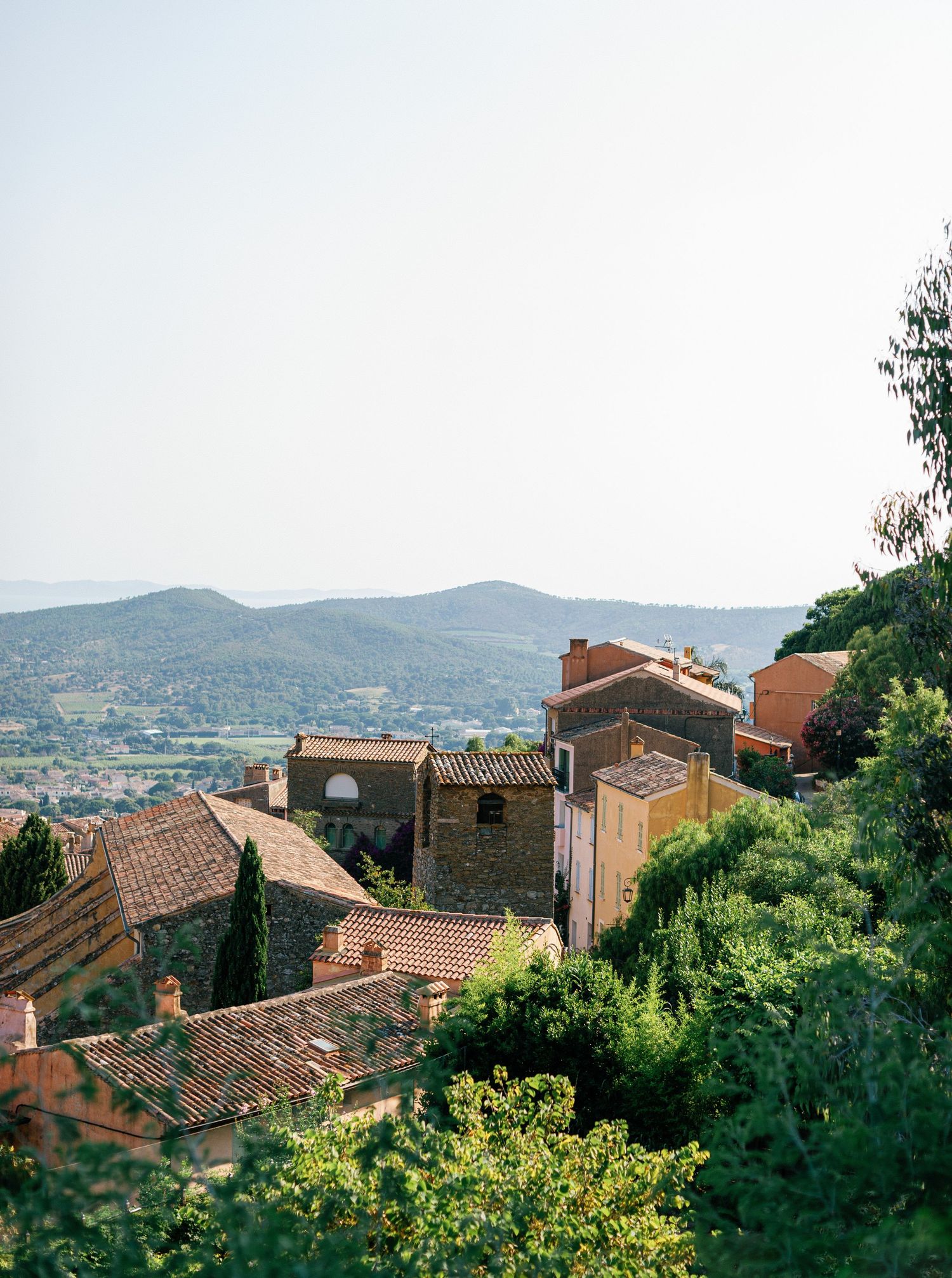 Panoramic view of traditional stone houses with terracotta roofs nestled in hills of Southern France on a sunny day.