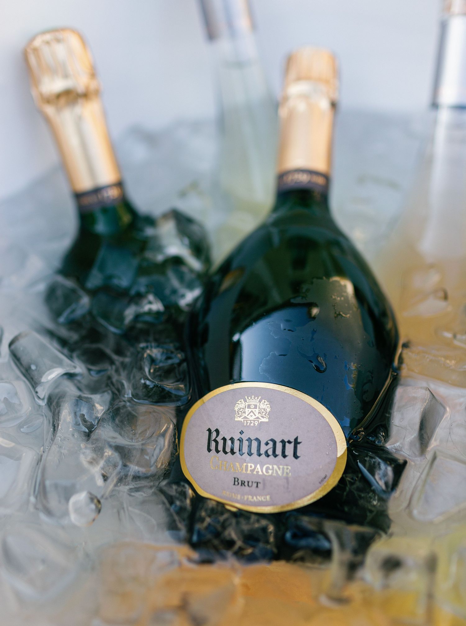 Chilled bottles of Ruinart champagne nestled in ice showcase the elegant oval label on dark glass bottles.
