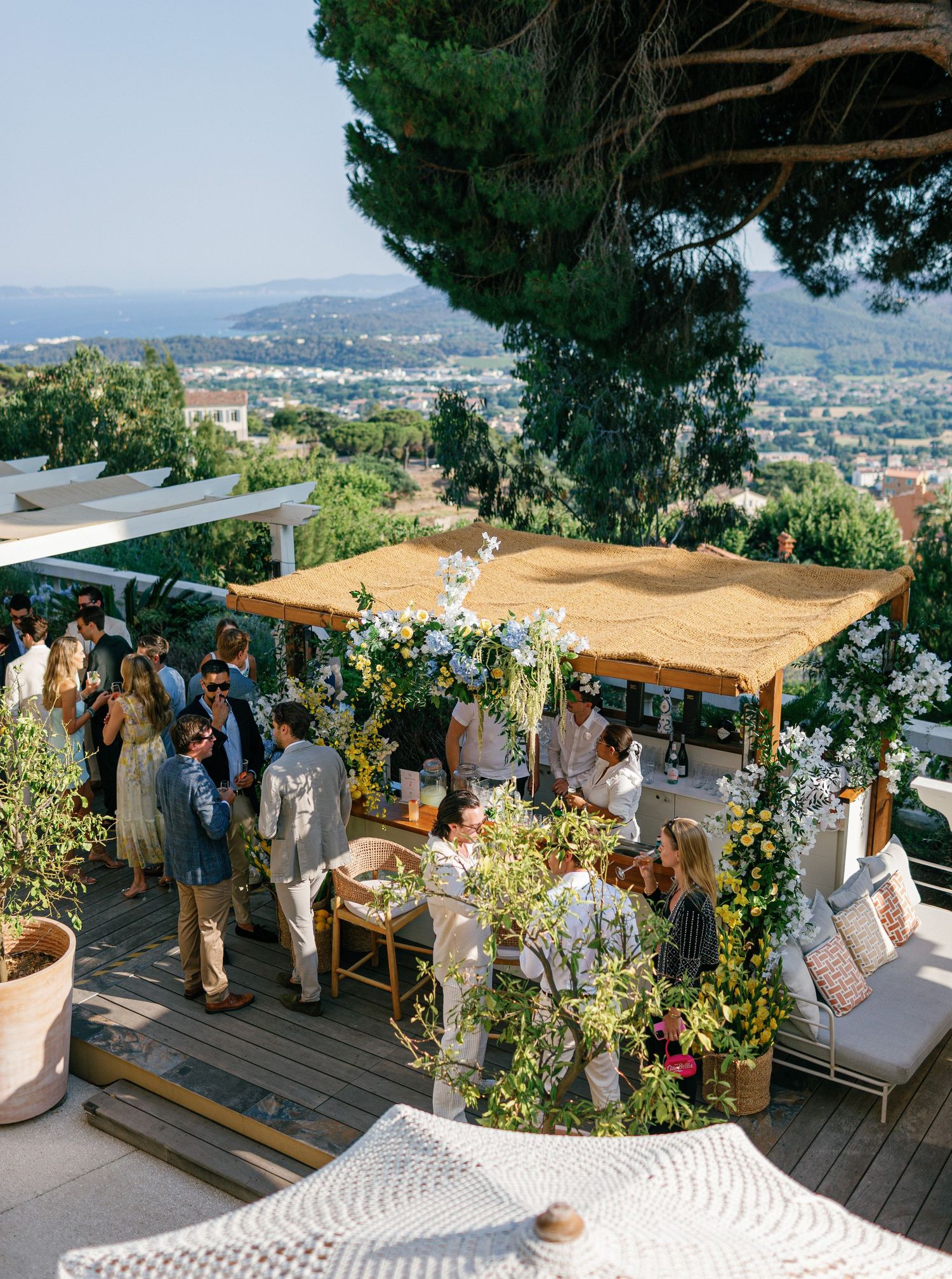 Guests mingle at an outdoor wedding reception on a terrace with scenic mountain views and beige canopy coverings  at Eden Rose Grand Hôtel.