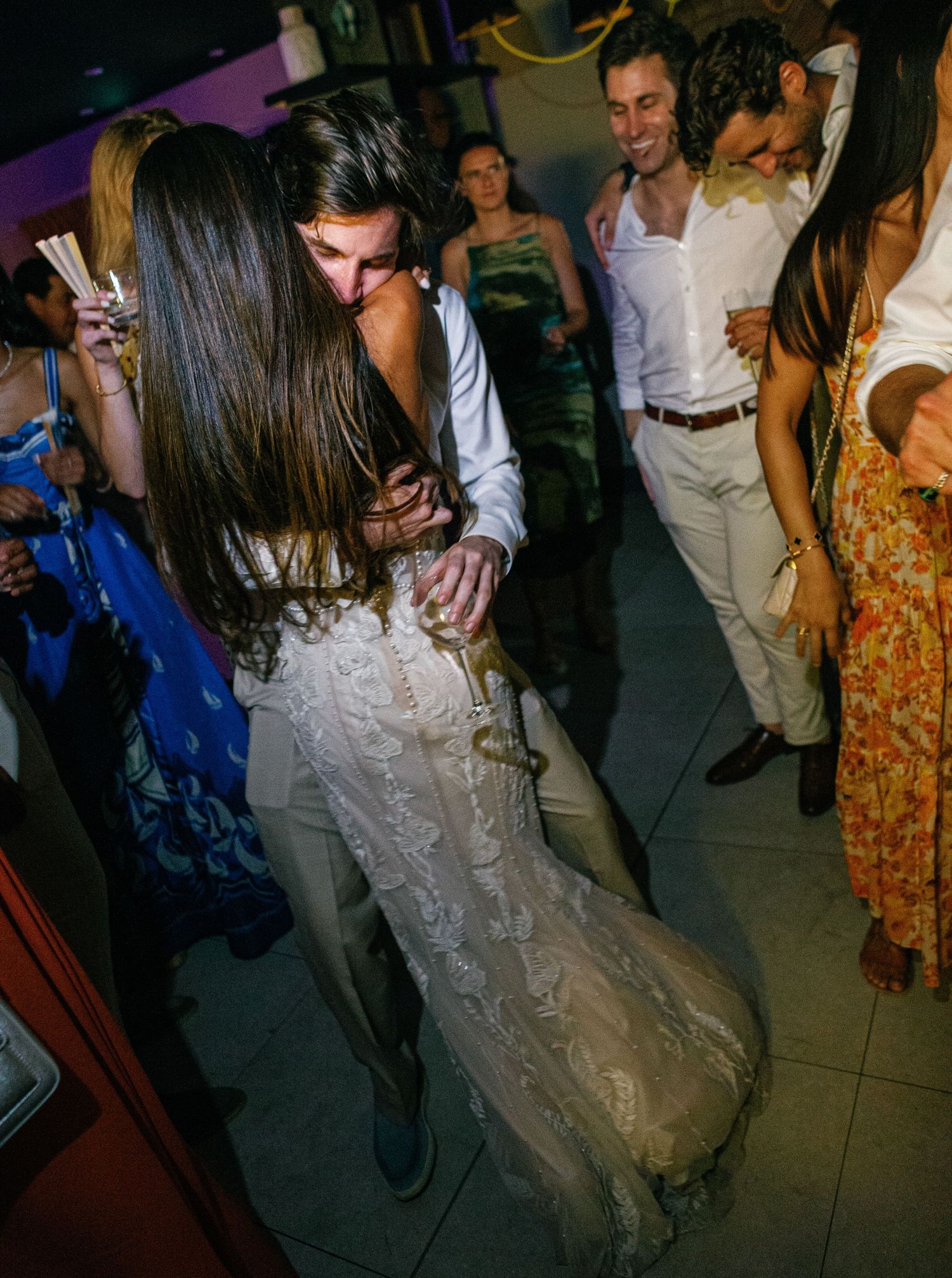 Couples dancing and enjoying themselves at a dimly lit wedding reception on the dance floor.