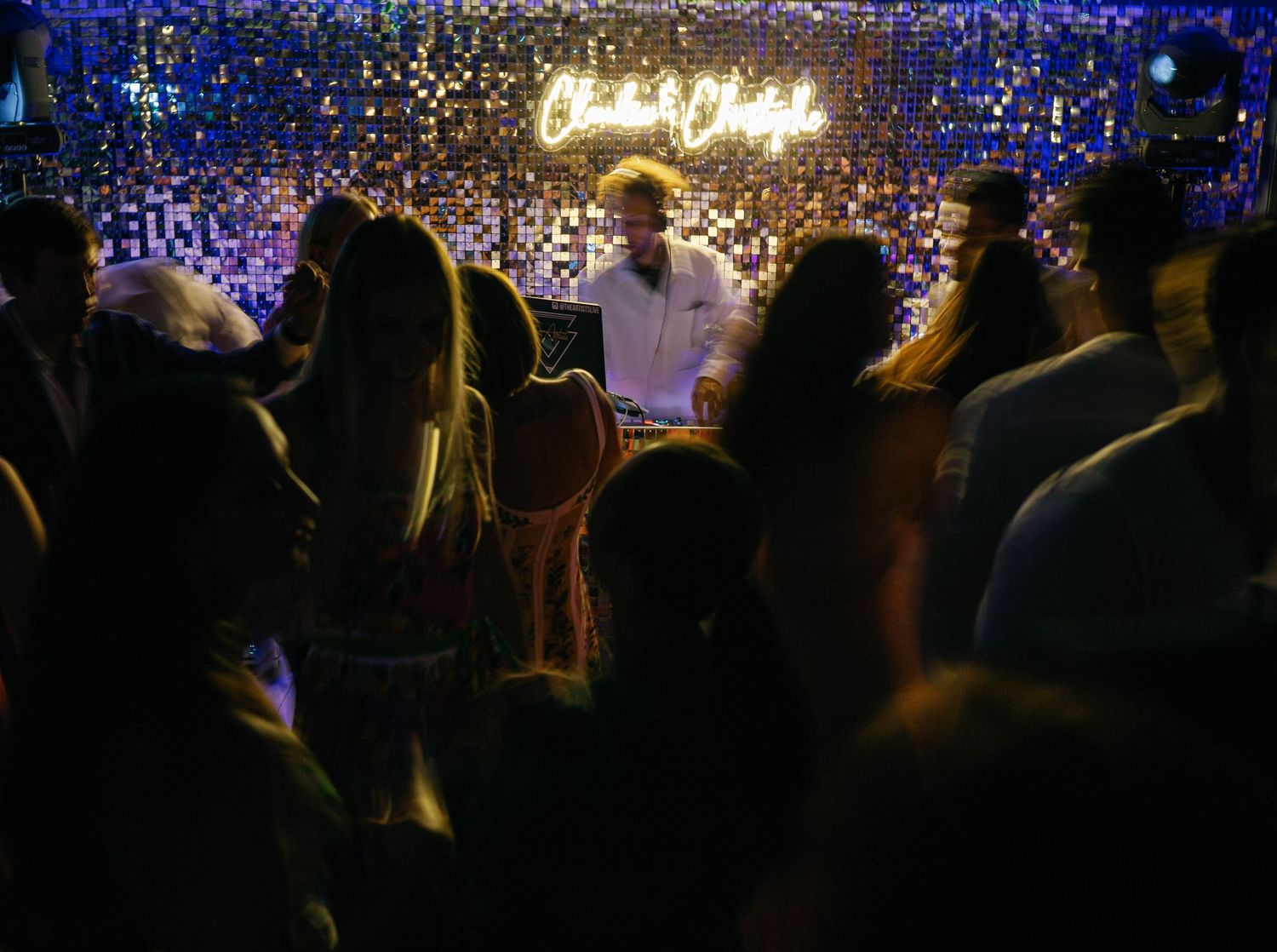 Crowd in dark concert venue with blue lighting and hanging string lights creating atmospheric ambiance on dance floor.