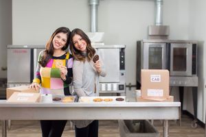 Friends enjoy cooking together and studying with drinks and snacks in a modern kitchen.