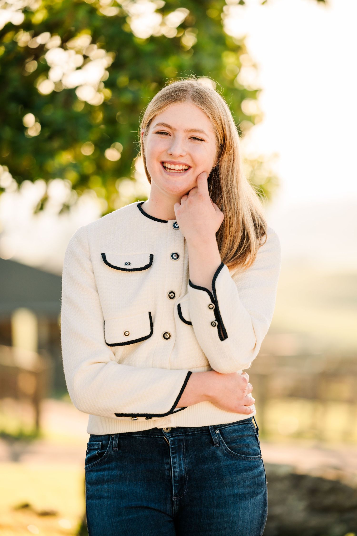Person in white sweater and jeans laughs joyfully during sunset outdoor portrait session.