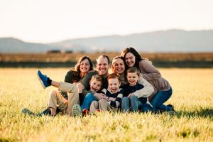 A playful group lies together in a golden wheat field at sunset, creating a warm and joyful outdoor portrait.