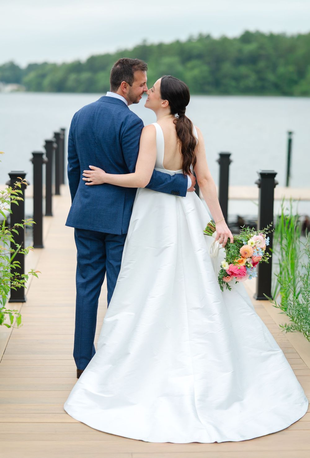 Newlyweds walking down the dock of the Lakehouse in Halifax, MA after their wedding. Photo by Joliette Marie Photography.