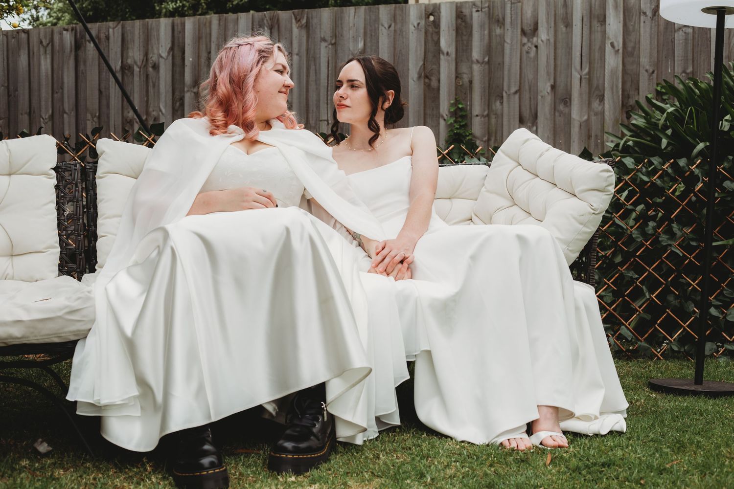 Two brides sit together in a garden, sharing intimate moments across four progressive shots.