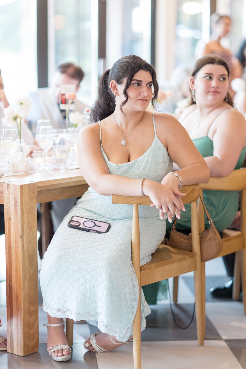 Woman in a mint green dress sits at a wooden table during a formal event.
