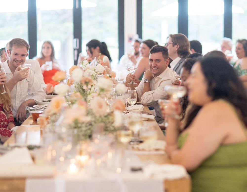 Elegant dinner party setup with glowing candles and floral centerpieces on long tables during an indoor reception.