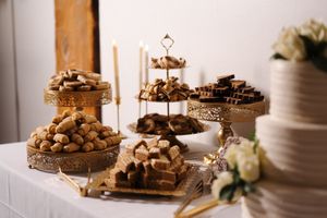 Multi-tiered dessert display featuring an assortment of treats on ornate gold stands with flowers nearby.