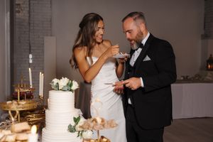 A couple shares their first bite of wedding cake together at their elegant indoor reception.