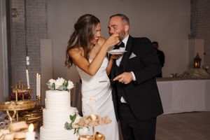 A couple in formal wedding attire share an intimate moment and meal during their wedding reception celebration.