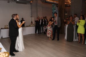 Couple dances their first dance at wedding reception in modern venue with light wood floors and white decor.