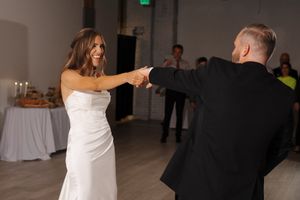 A couple shares an energetic moment on the dance floor, with the bride in white and partner in black sharing a dance move.