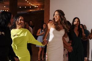People dancing and celebrating together at a lively party with string lights in the background.