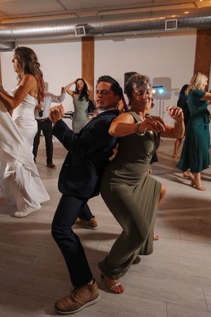 Wedding guests dancing and having fun on the dance floor at an indoor reception venue.