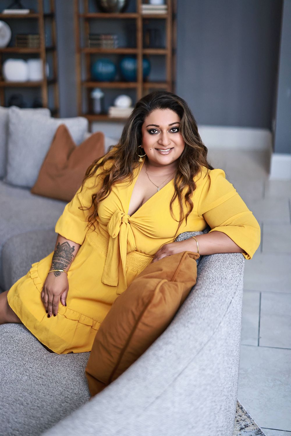 Lifestyle branding portrait of psychologist in a bright yellow dress on a modern gray couch.