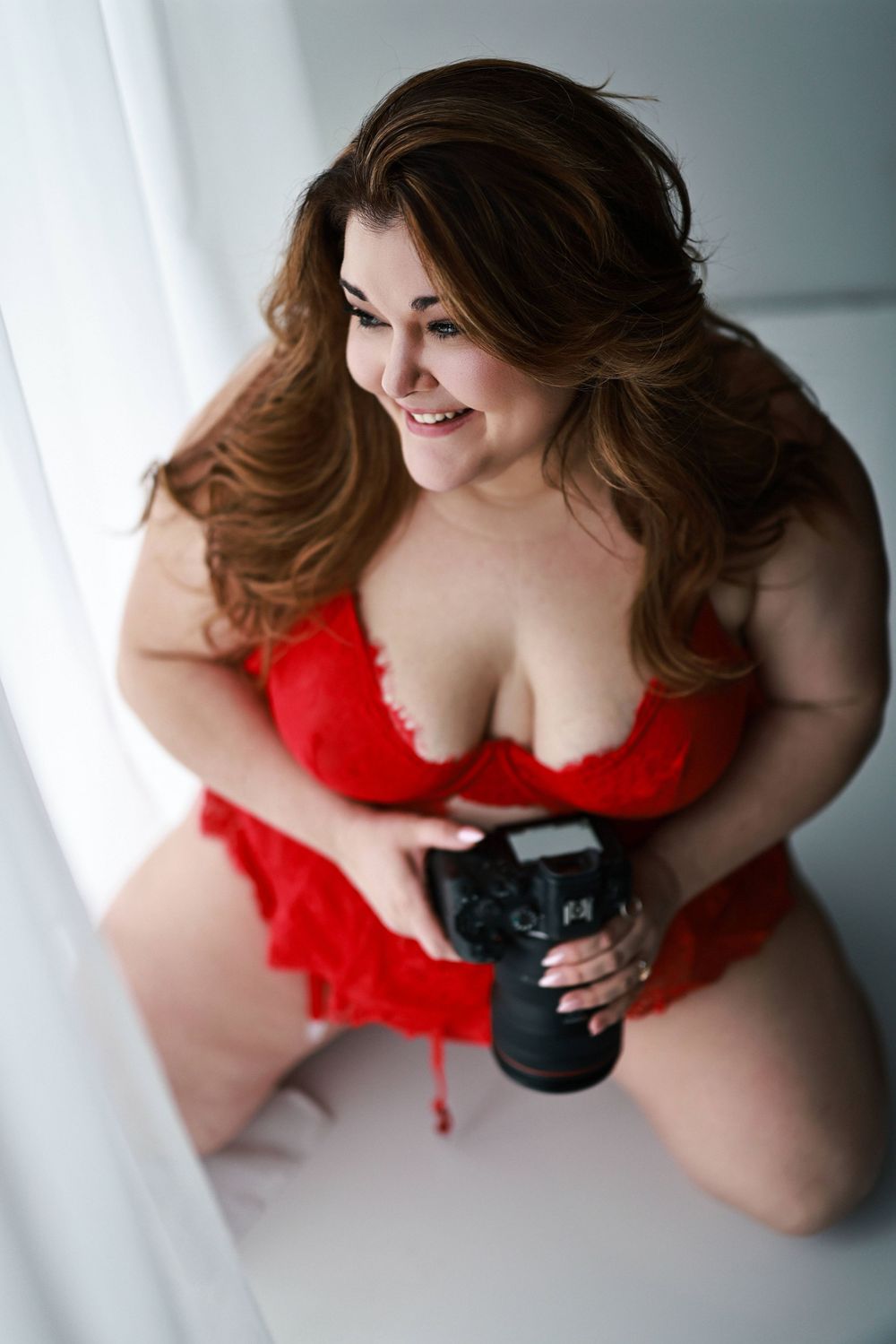 Intimate boudoir photography session with red lingerie and soft lighting.