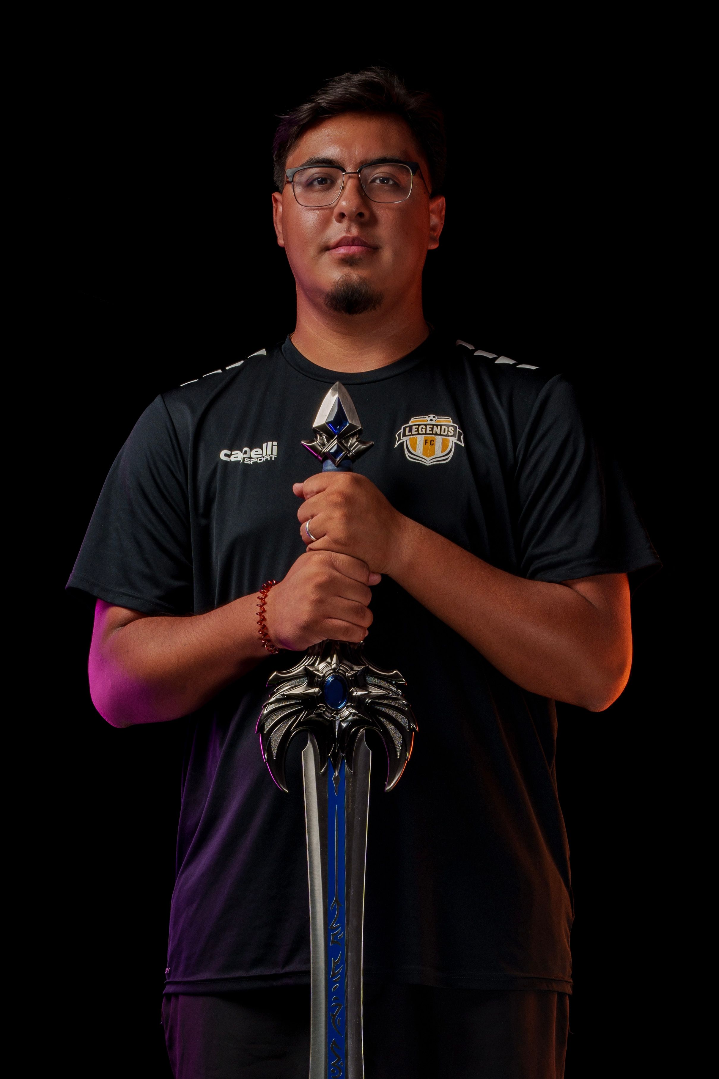Soccer Coach wearing glasses holds a sword against dark background with dramatic lighting.