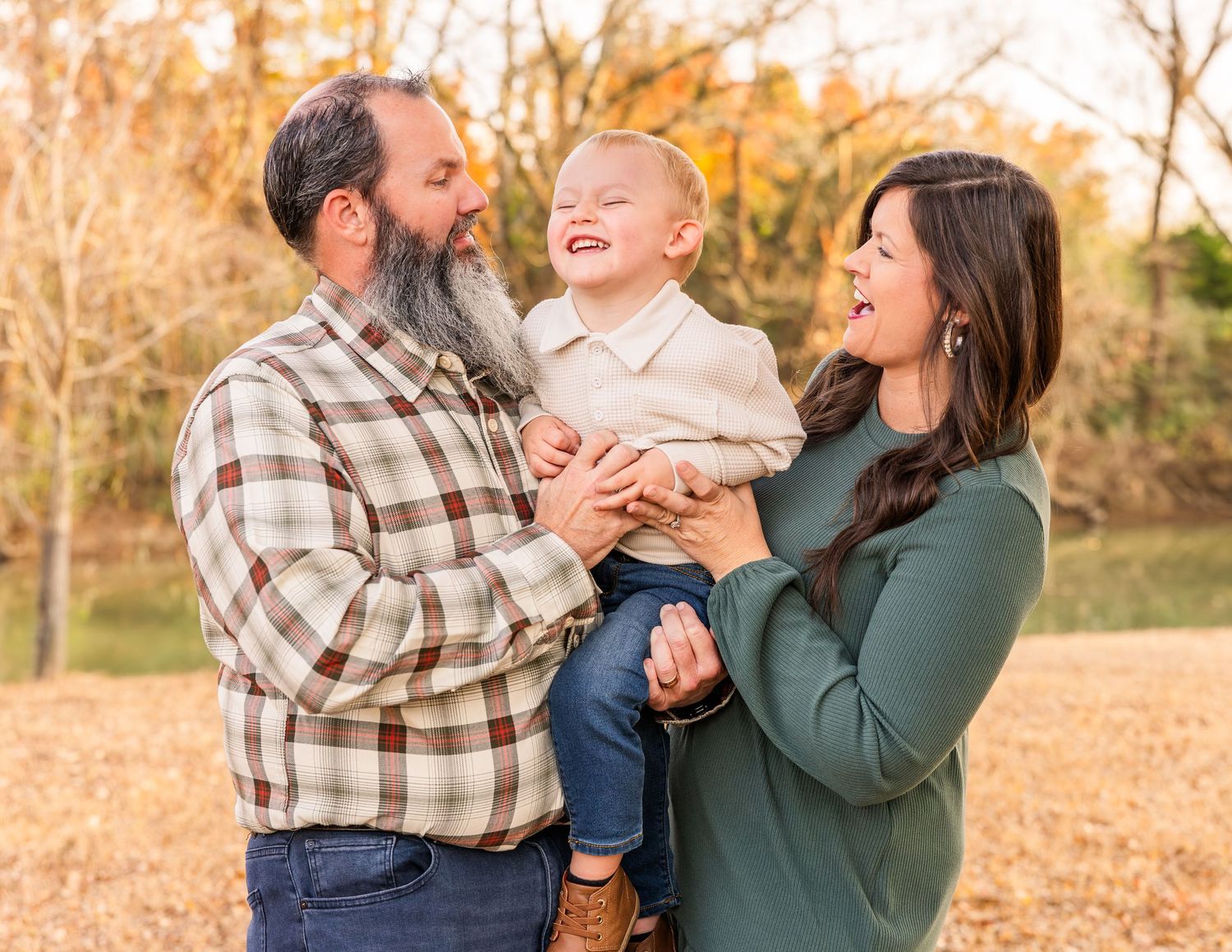 A cozy family snuggled together on a teal blanket during an autumn outdoor photoshoot.