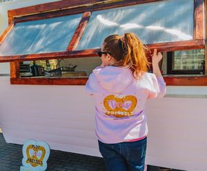 Five connected photos show someone cooking burgers at an orange Whataburger mobile food truck at an outdoor event.