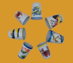 Circular arrangement of decorative ceramic glasses featuring colorful sea creature designs on an orange background.