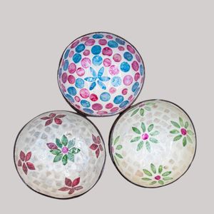 Hand-painted, hand-carved bowls decorated with pink and blue polka dots and floral designs against a light gray background.
