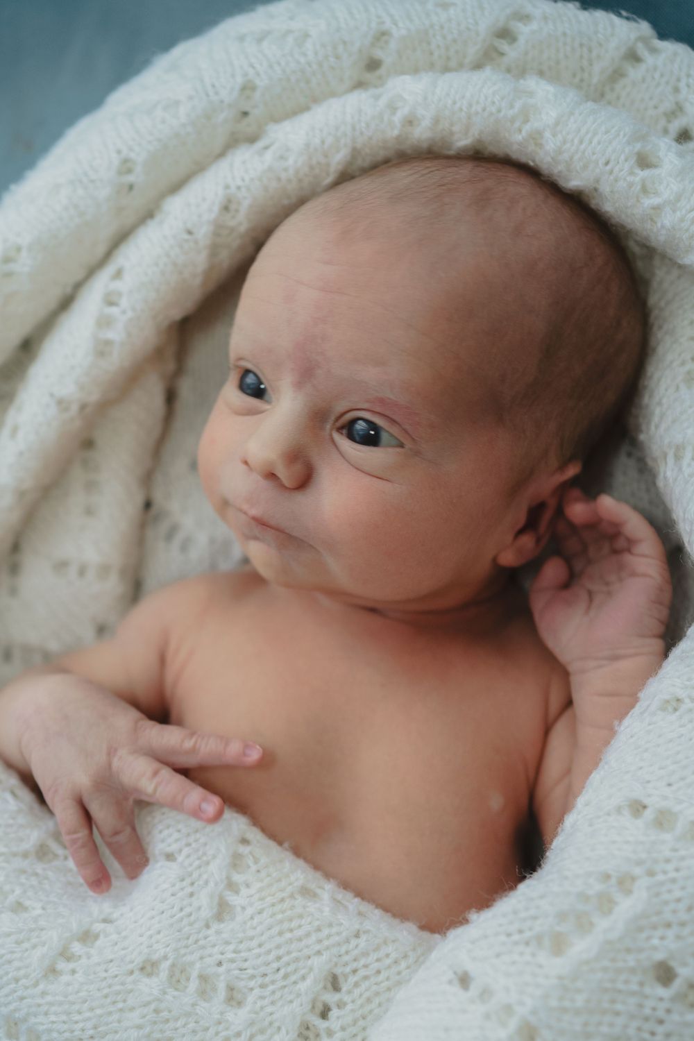 a newborn baby gently wrapped in a blanket with big sparkly eyes