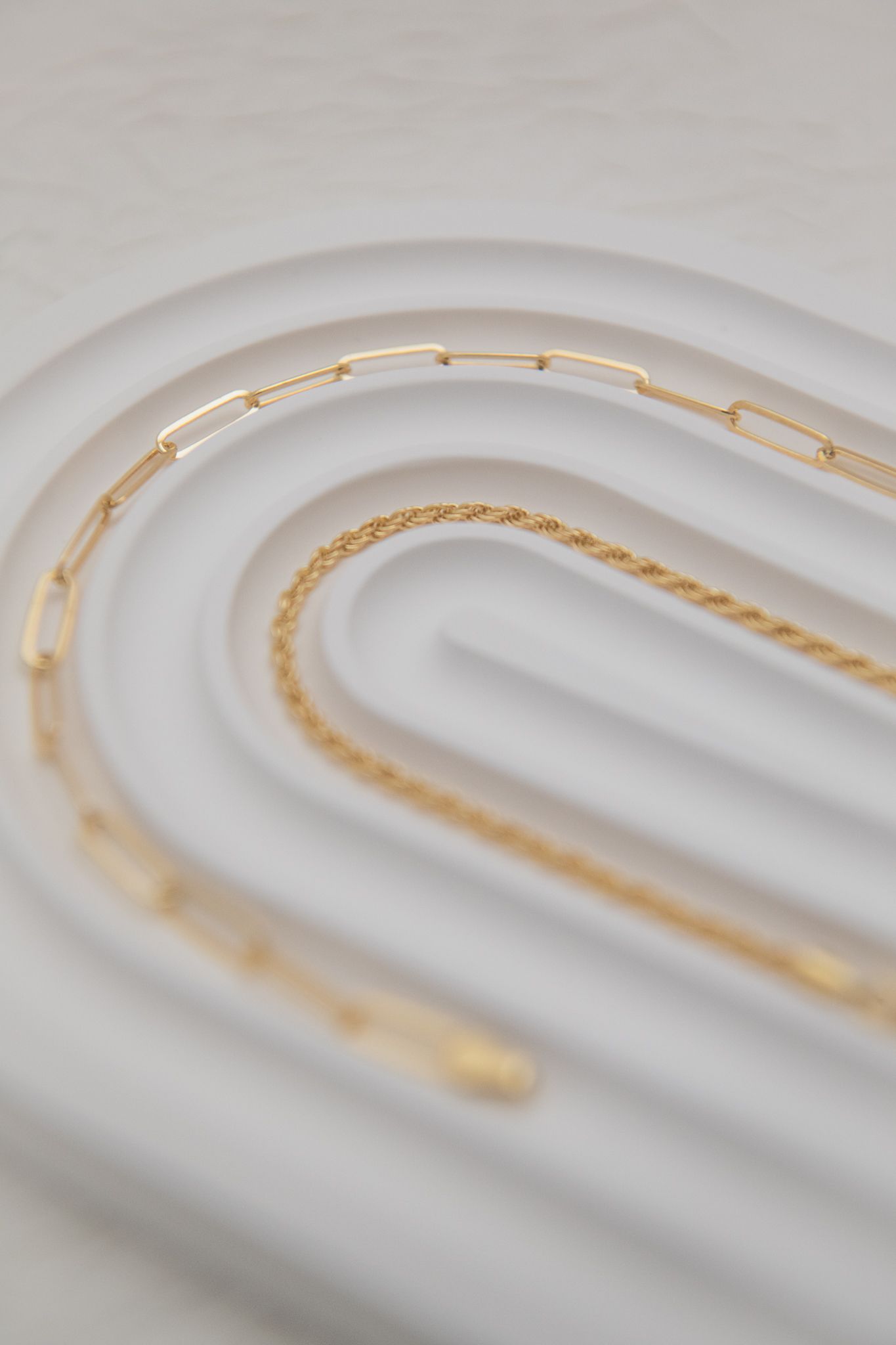Close-up professional product photography of a gold chain on a curved white background - studio lighting, shot in Blackwood, South Wales