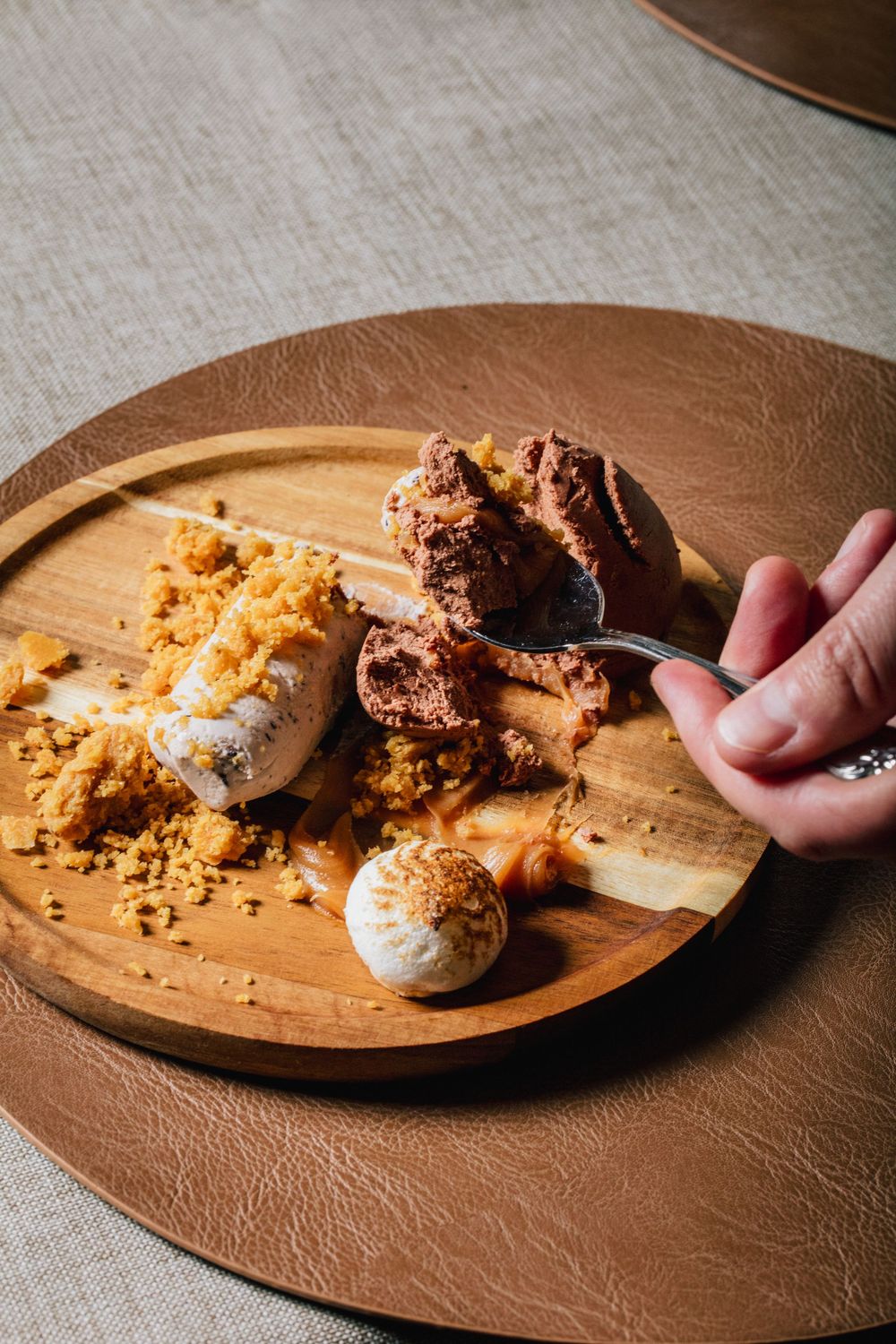 A wooden serving board displays partially eaten cookies and crumbs against a light colored tablecloth.
