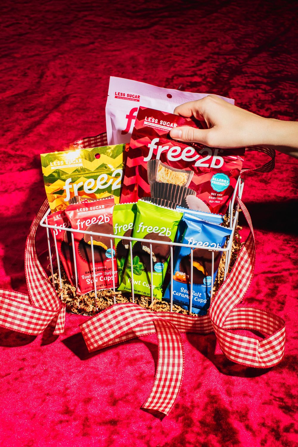 Colorful snack bar packages arranged in a red checkered basket against a red velvet background.