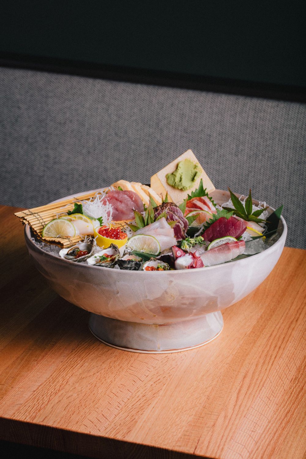 Large bowl of assorted sashimi and seafood served on ice with traditional garnishes.