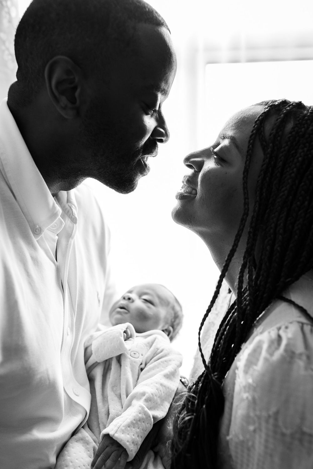 Black and white silhouette of parents holding their newborn baby