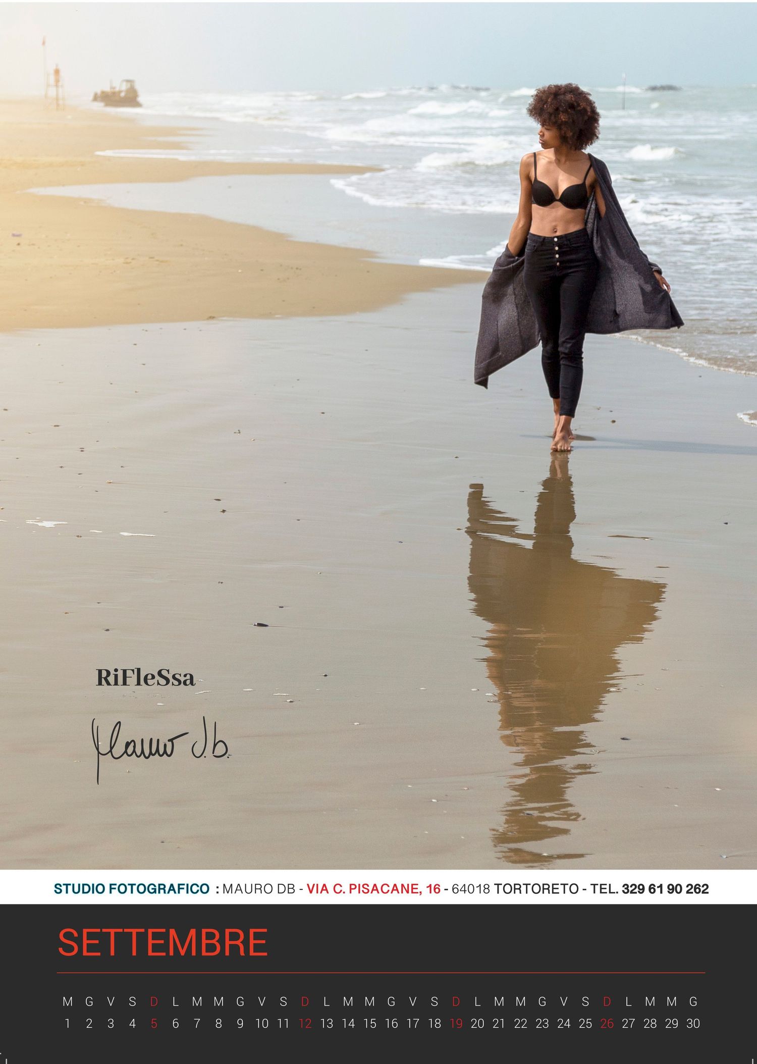 Silhouetted figure walking along a sandy beach at sunset with reflection in wet sand.