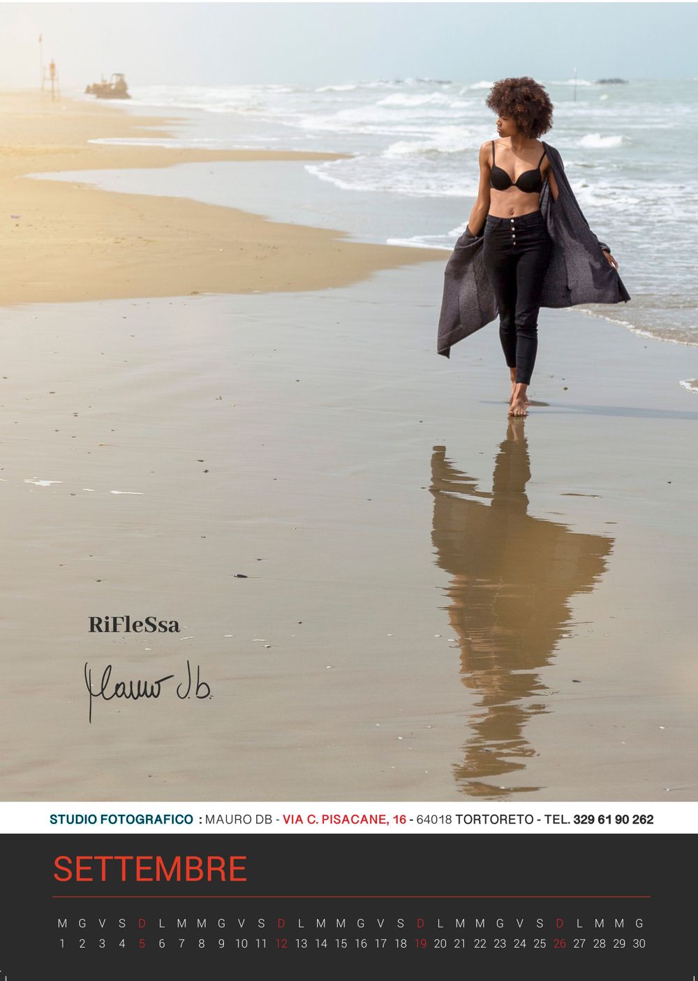 Silhouetted figure walking along a sandy beach at sunset with reflection in wet sand.