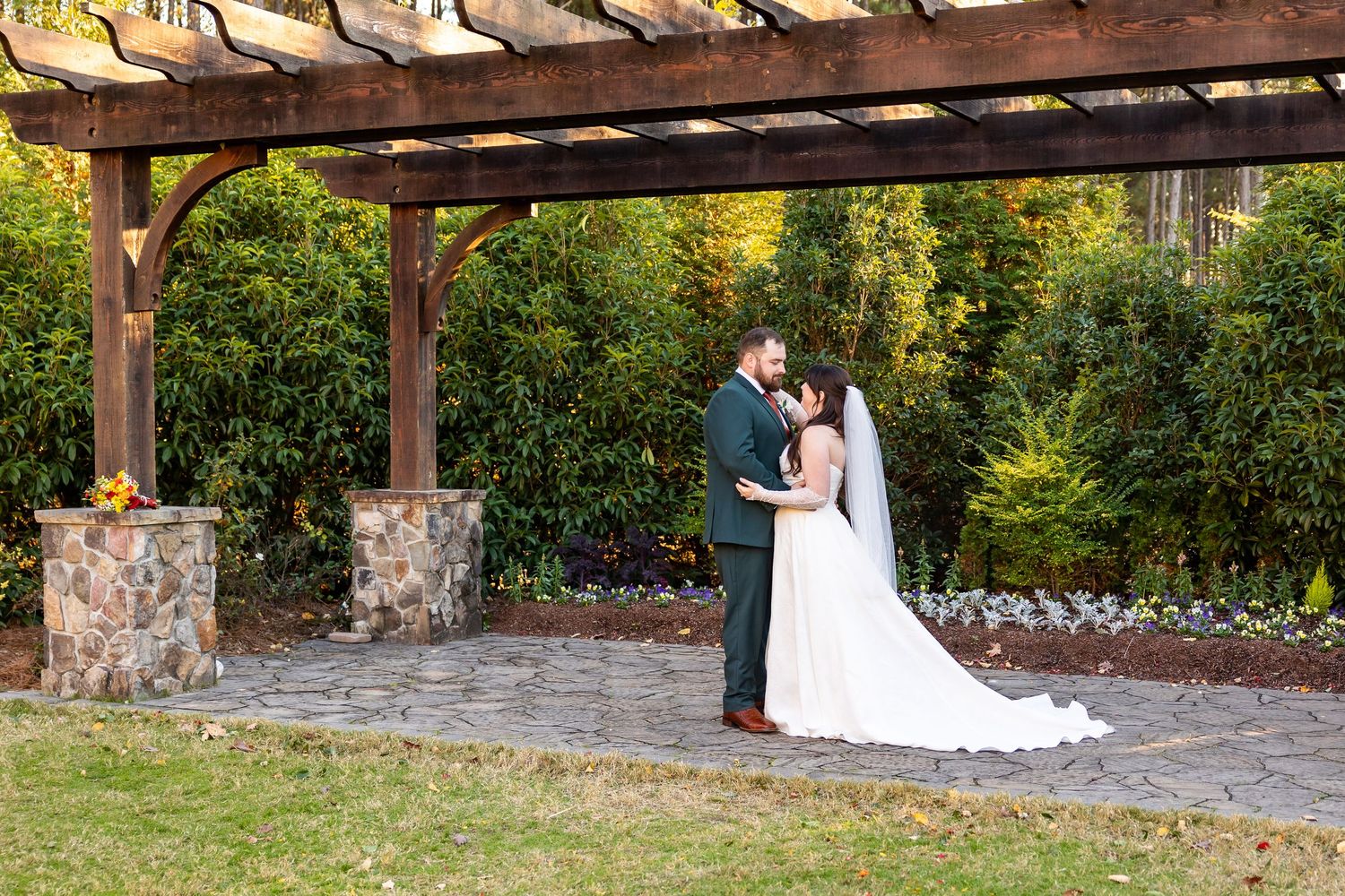 Romantic outdoor wedding venue with wooden pergola and stone details at sunset (Clayton, NC).