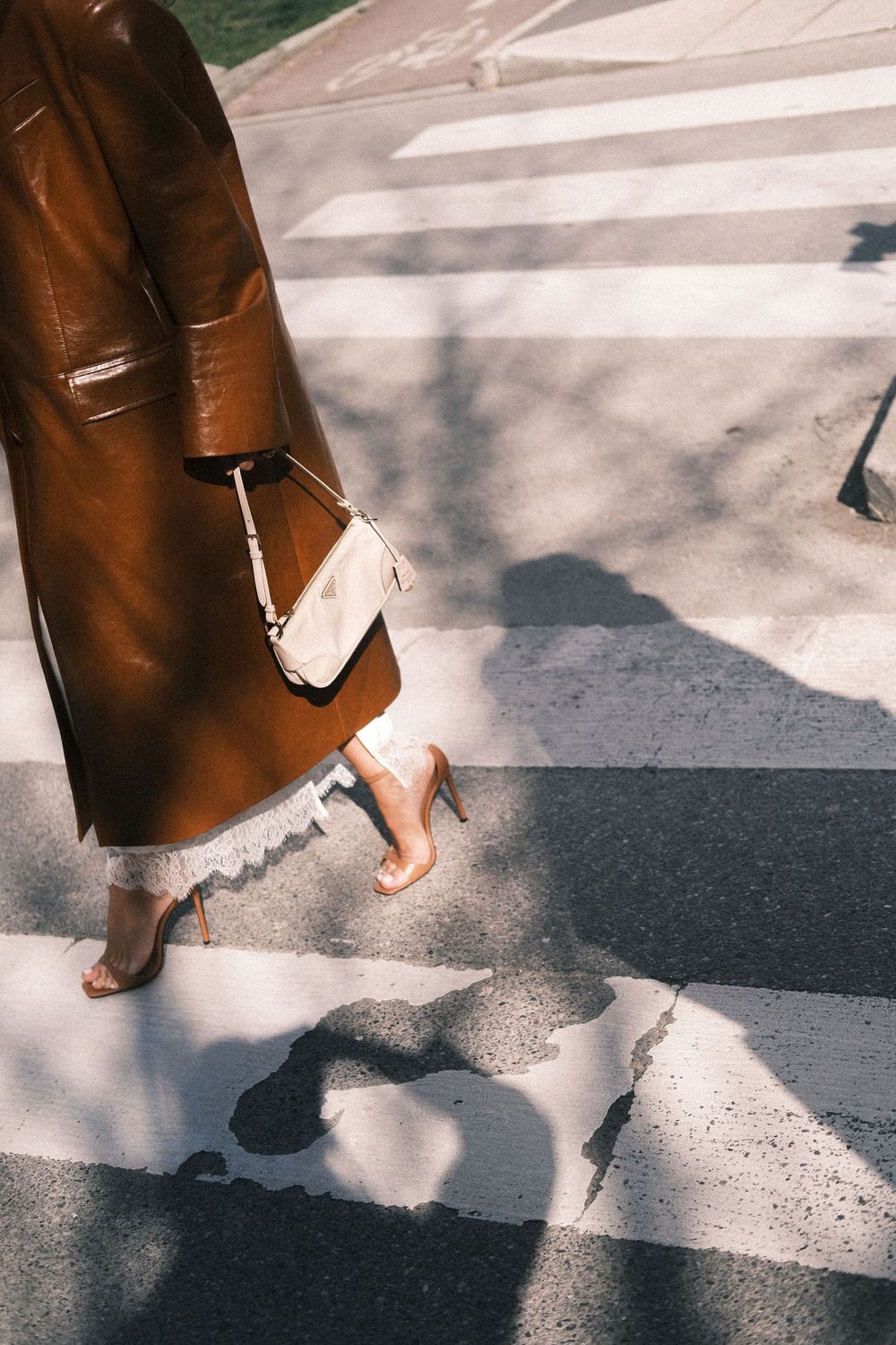 Artistic shot of brown leather coat and lace hem crossing striped pedestrian crossing.
