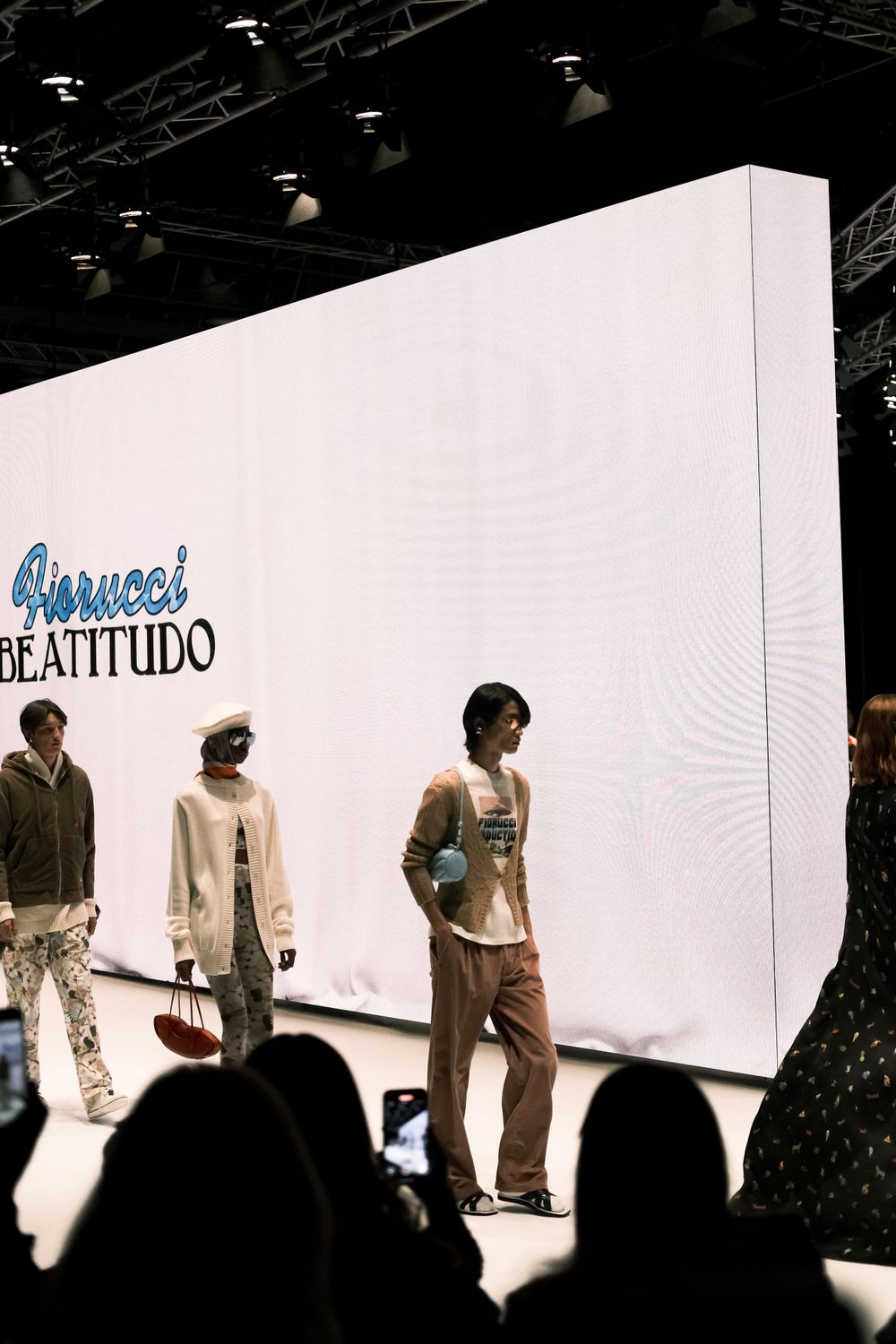 Models walking a fashion runway with white backdrop and 'Beattitudo' text display.